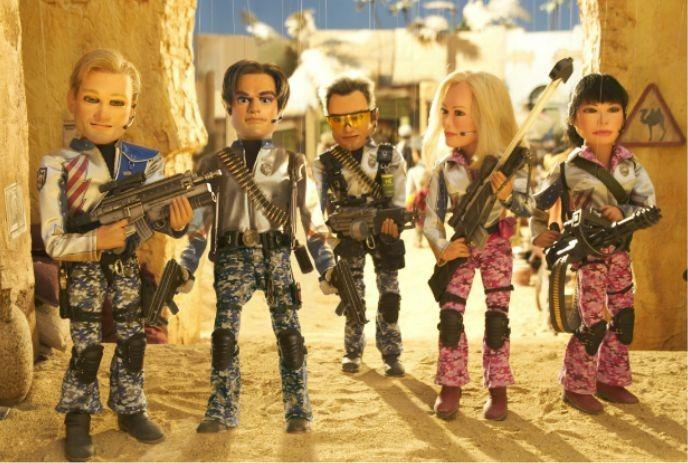 Five action-figure characters in military gear, holding weapons, standing in a sandy, desert-like environment.