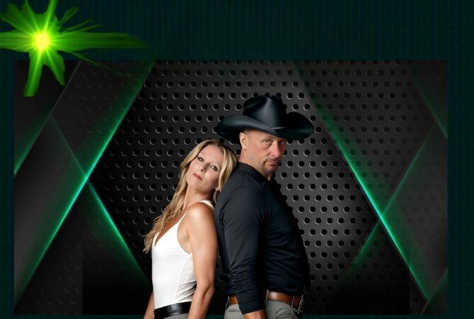 A man in a black hat and a woman in a white top stand back-to-back against a dark, perforated background with green accents.