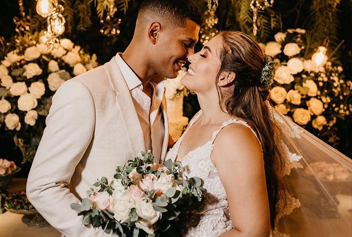 A photo of a couple on their wedding day, happy and smiling, dressed in wedding attire looking at each other.