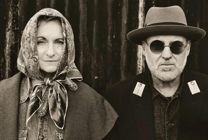 A sepia-toned photograph of Michael Weston King and Lou Dalgleish with one wearing a headscarf and the other a hat.