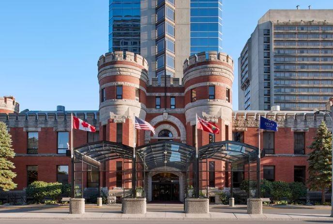 A modern glass high-rise building stands behind a historic red-brick structure with turrets.