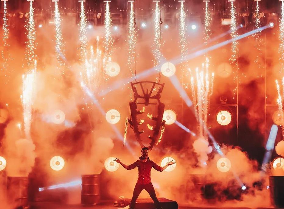 A magician on stage with pyro technics, smoke and bright lights for the production of Champions of Magic