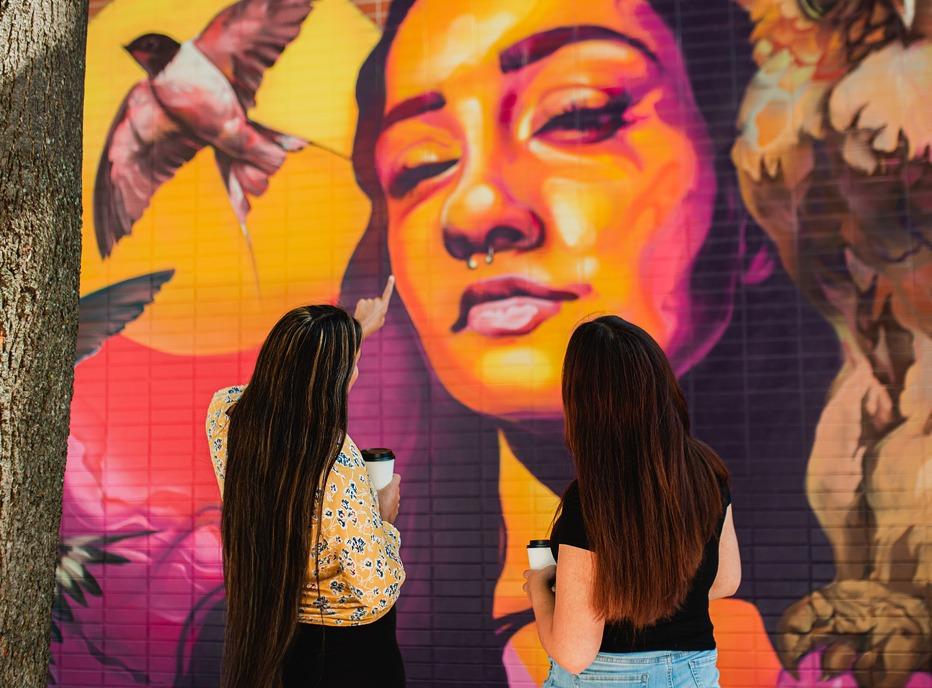 Two females looking at a vibrant mural located in London, Ontario