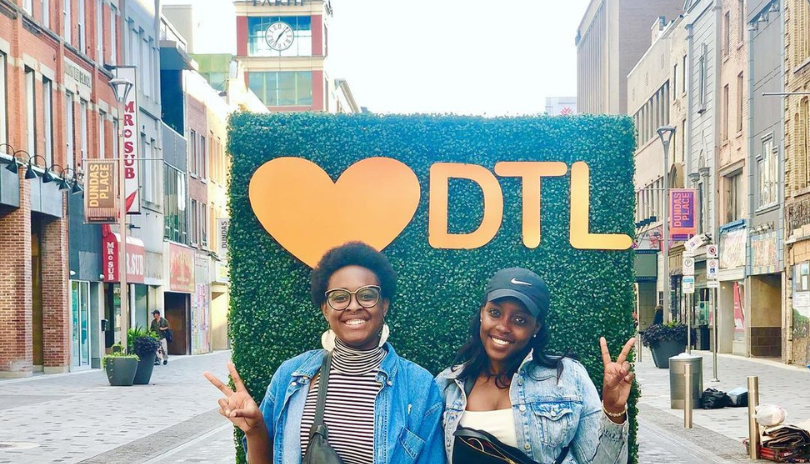 Women posing in front of a Downtown London sign