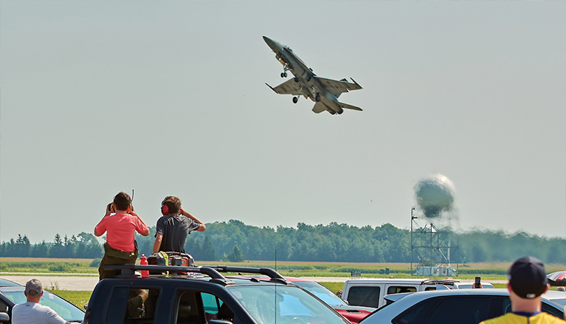 Fighter Jet flying overhead as viewers from the ground look up in awe