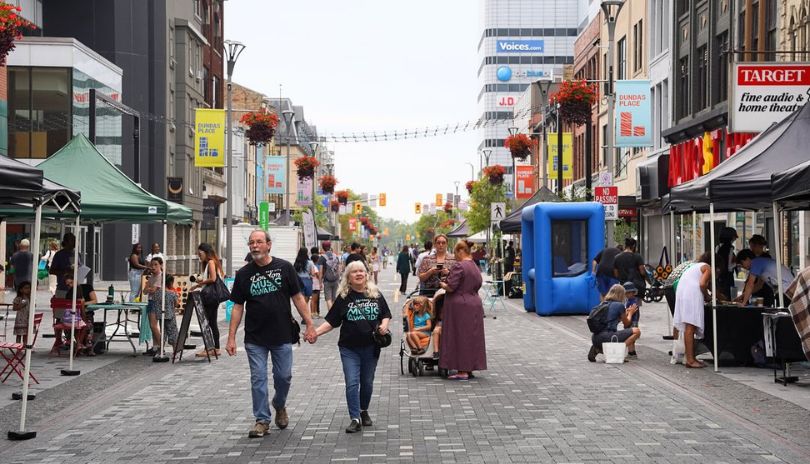 A couple walking together while holding hands at Dundas Place during a market.